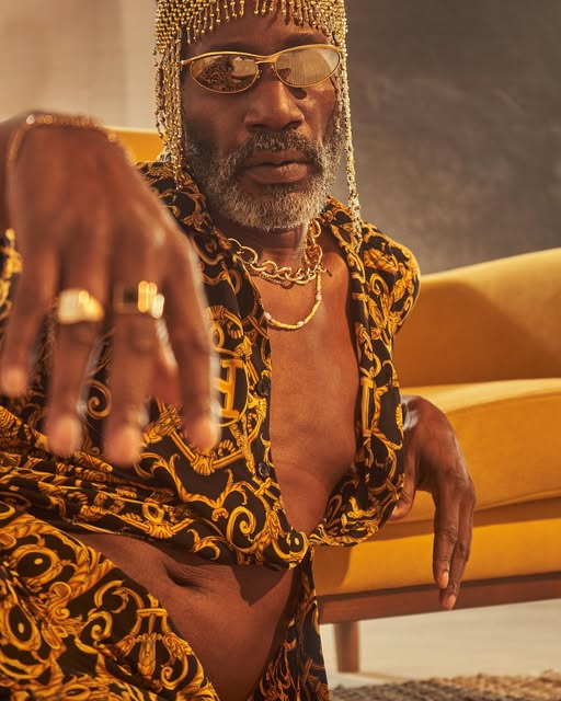 Portrait of a man in gold accessories and a black and gold patterned outfit